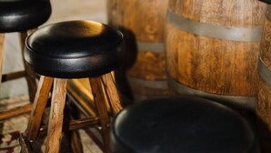 A bar area with wooden stools and barrels.