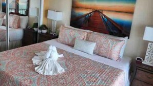 Een hotelkamer met een bed, een schilderij van een zonsondergang boven een brug en een spiegel aan de muur.