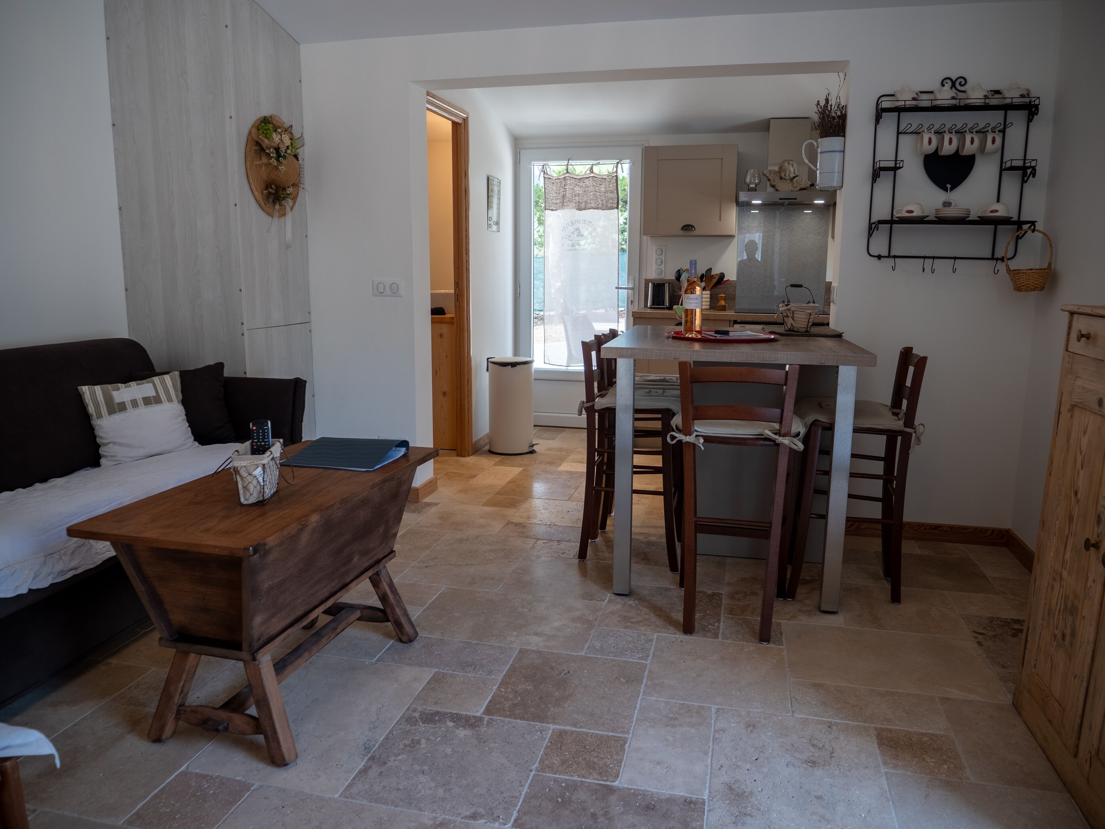 A compact living space with a sofa, a wooden table, and a kitchen area with a dining table and chairs.