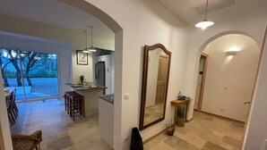 A spacious living area with a dining table, chairs, a large mirror, and a kitchen in the background. - Coeur de Lavande - Maison climatisée avec piscine (Fox-Amphoux)