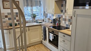 A modern kitchen with white cabinets, a stainless steel refrigerator, and a wooden floor.