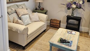 A living room with a beige sofa, a coffee table, a fireplace, and a mirror on the wall.