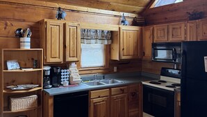Una cocina acogedora con armarios de madera, microondas integrado y refrigerador negro.