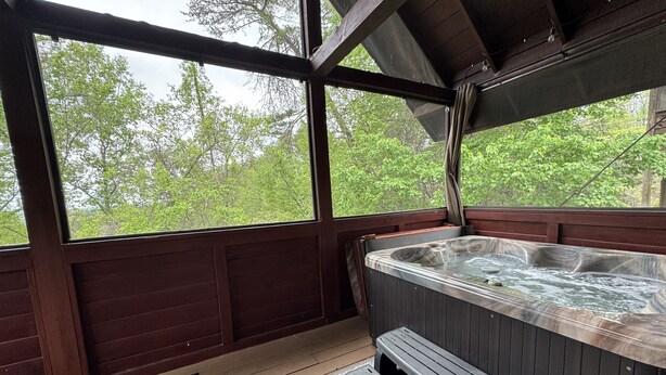 Un jacuzzi en un área de terraza de madera con vista a árboles.