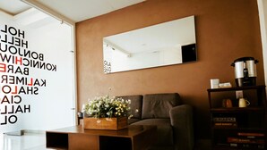 A modern living room with a sofa, a coffee table with flowers, a bookshelf, and a large mirror on the wall. - A11 SUPER SUITE PREMIUM AT PLAZA ACEQUIA (Cuautitlan Izcalli)