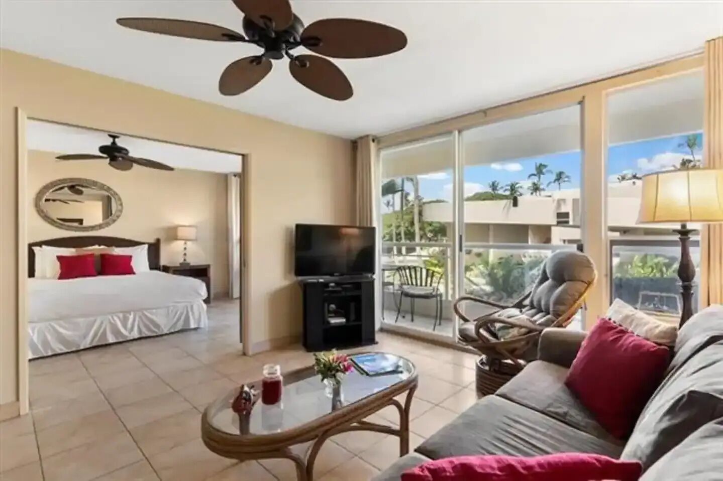 Quarto de hotel com varanda, uma cama, televisão, mesa de centro e sofá.