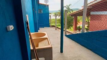A simple space with a sink and stool, surrounded by a blue fence and a brick building.