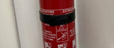 A red fire extinguisher mounted on a white wall.