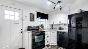 A modern kitchen with white cabinets, a black refrigerator, and a black oven.
