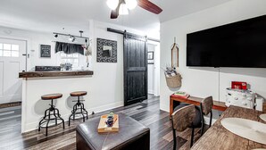 A modern kitchen with a black door, wooden stools, and a bar area.