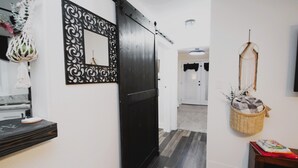 A hallway with a black sliding door, a decorative mirror, a woven basket, and a small table with books.
