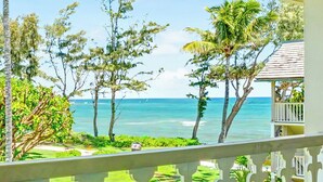 A view from a balcony overlooking a beach with palm trees and a clear sky. - New from Premier Host -  Top Floor Oceanview Studio at Islander on the Beach (Kapaʻa)