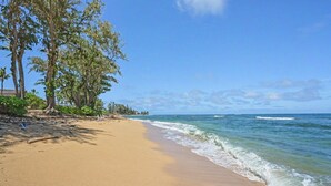 A beach with clear skies, calm waves, and trees along the shore. - New from Premier Host -  Top Floor Oceanview Studio at Islander on the Beach (Kapaʻa)
