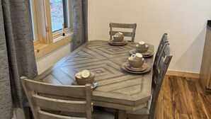Zona pranzo con tavolo in legno, sedie e finestra con tende.
