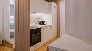 Una cuina moderna amb armaris blancs, forn integrat i taulell amb cafetera.