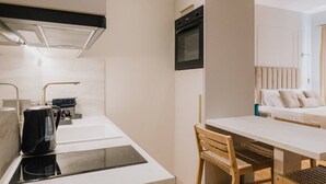 Une cuisine compacte au design moderne, dotée d’un four encastré, d’une machine à café et d’un évier.