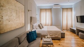 Une chambre moderne avec un grand lit, un canapé, une télévision et un appareil de climatisation.