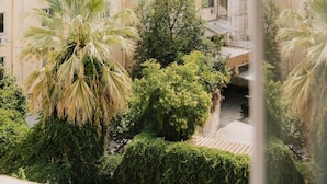 A view of a residential area with multiple buildings, some with balconies, and lush greenery including palm trees. - Mantzarou #6 - Corfu Town Luxury Suites

 (Kerkira)
