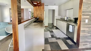 Une cuisine moderne avec un mur d’accent en bois, une cuisinière encastrée et une machine à café.