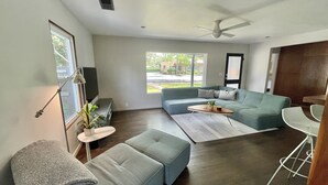 Un salon moderne avec un canapé d’angle, une table basse et un ventilateur de plafond.