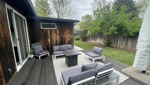 Une terrasse dotée de mobilier d’extérieur, notamment de canapés et d’une table basse, ainsi qu’une petite structure en bois avec une fenêtre.