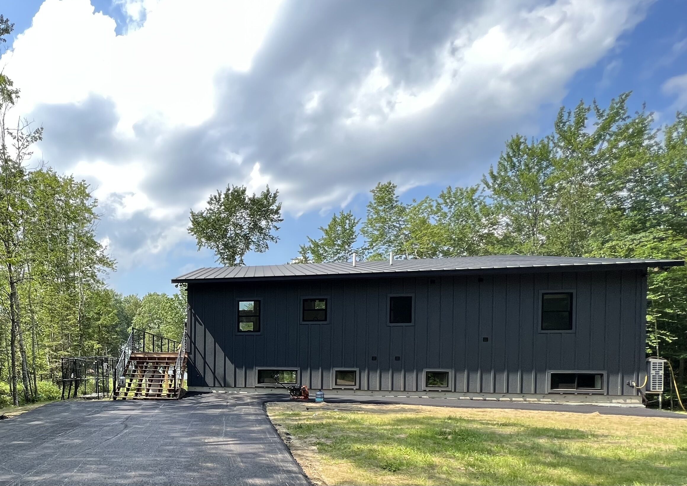 A modern two-story building with a metal roof, multiple windows, and a paved driveway.
