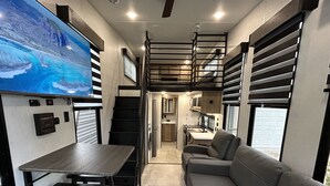 A compact RV interior with a kitchenette, a dining area, and a seating area. - New tiny house near Grass Valley - hot tub access! (Rough and Ready)