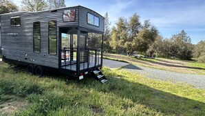 A mobile home with a two-story structure, a covered porch, and a ramp leading to the entrance. - New tiny house near Grass Valley - hot tub access! (Rough and Ready)