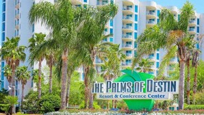 Un complexe hôtelier appelé « The Palms of Destin », doté d’un bâtiment moderne et bordé de palmiers.