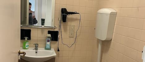 A small bathroom with a sink, toilet, bidet, and a mirror.
