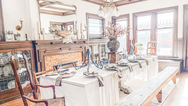 A dining area with a long wooden table set for a meal, surrounded by chairs. - Sandusky's Original Luxury Bachelorette Mansion  (Sandusky)