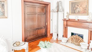 A room with a large wooden door, a fireplace with decorative items, and a chandelier. - Sandusky's Original Luxury Bachelorette Mansion  (Sandusky)
