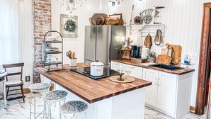 A kitchen with a central island, wooden countertops, a stainless steel refrigerator, and a chandelier. - Sandusky's Original Luxury Bachelorette Mansion  (Sandusky)