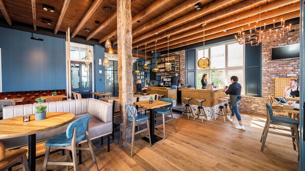 Een gezellig restaurant met houten balken, blauwe muren en een bar.