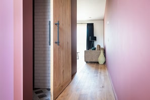 Un couloir doté d’un plancher en bois, d’un mur en briques et d’une porte avec des poignées noires.