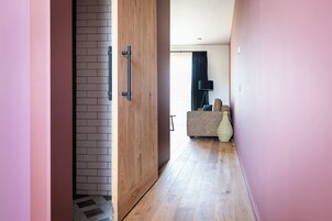 A hallway with a wooden floor, a brick wall, and a door with black handles.