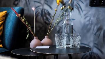 A small round table with two pink vases, a clear glass pitcher, and two clear glass cups.