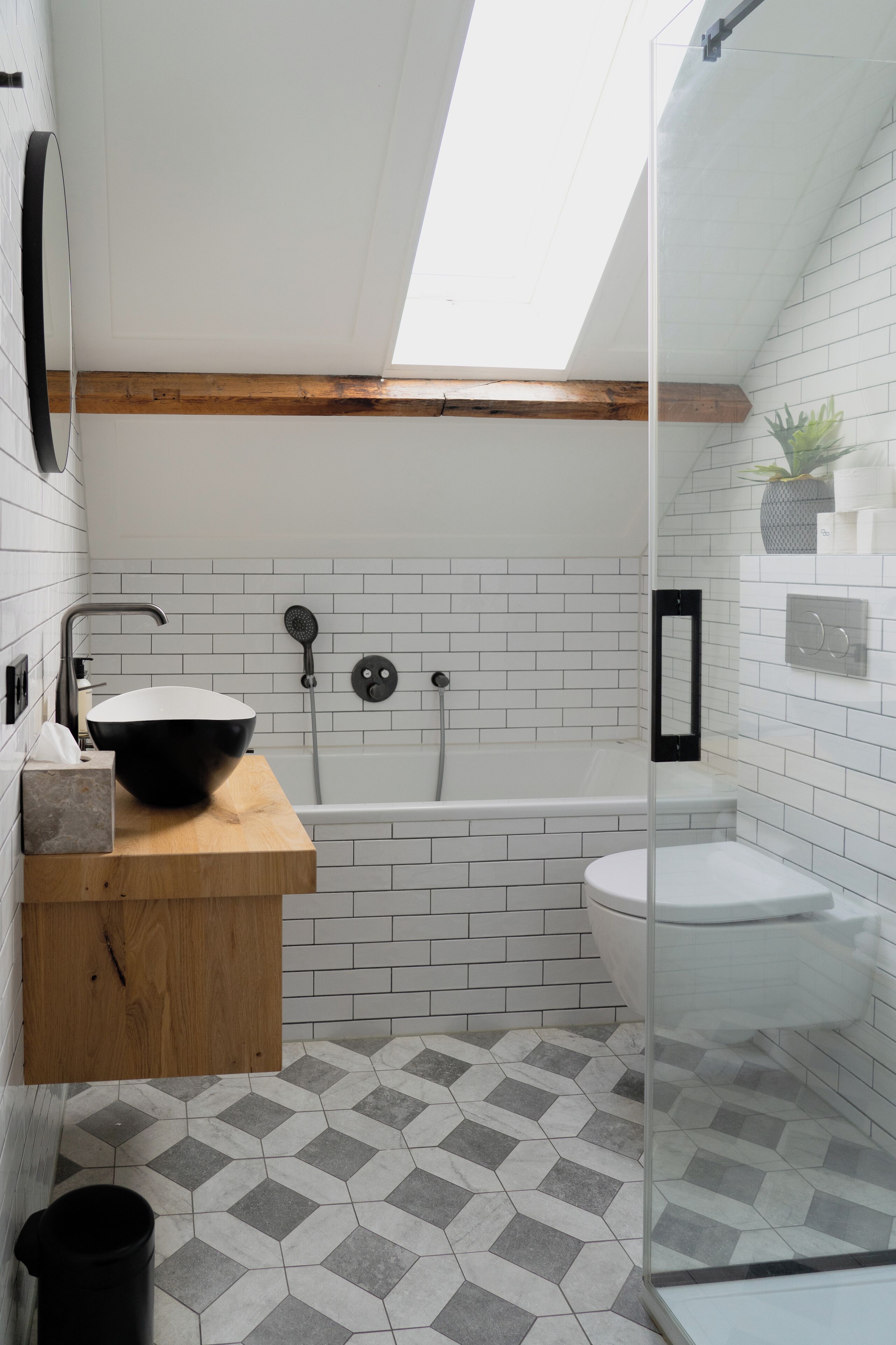 A modern bathroom with a skylight, a freestanding bathtub, a sink with a wooden countertop, and a toilet.