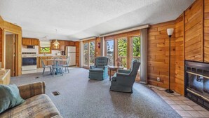 Een gezellige woonruimte met een bank, twee fauteuils, een eettafel met stoelen, een keuken en een open haard.