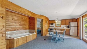Een chalet met houten inrichting, een keuken, een eettafel met stoelen en een groot raam.