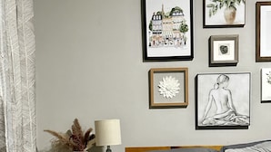 Un dormitorio con una cama, una mesita de noche con lámpara y una pared decorada con cuadros.