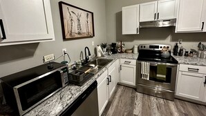 Una cocina moderna con armarios blancos, estufa de acero inoxidable, microondas y lavavajillas.