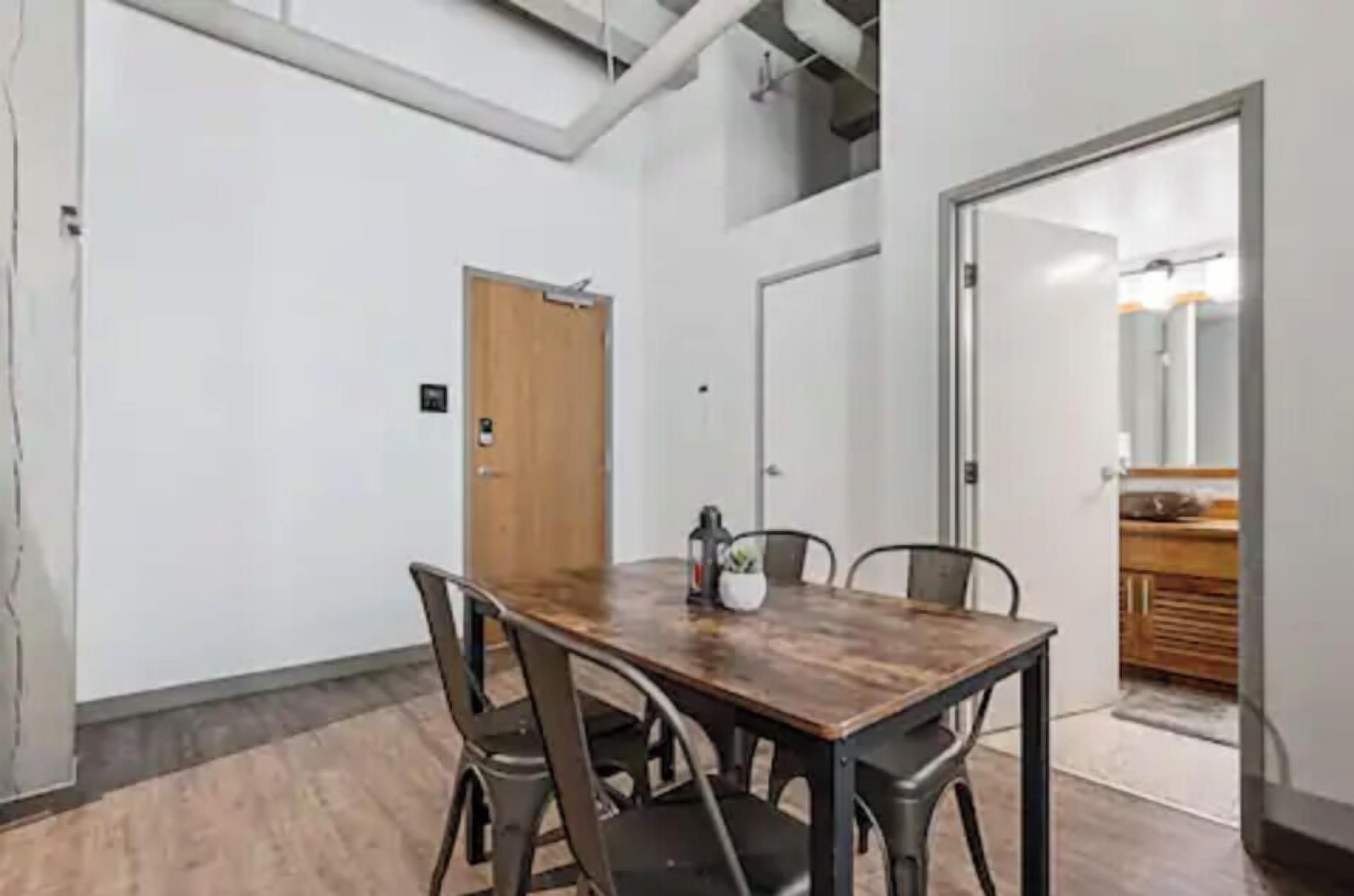 A conference room with a wooden table, four chairs, and a door.