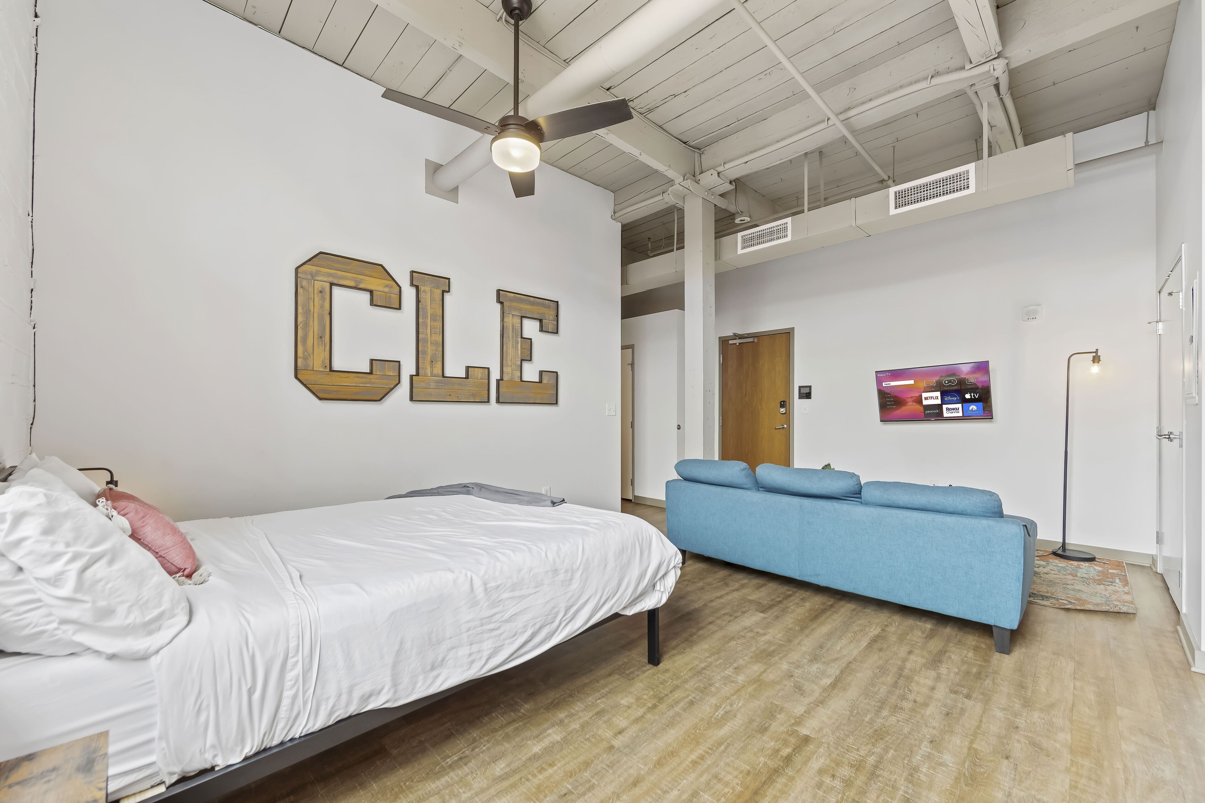 A modern room with a bed, a blue sofa, and a ceiling fan.
