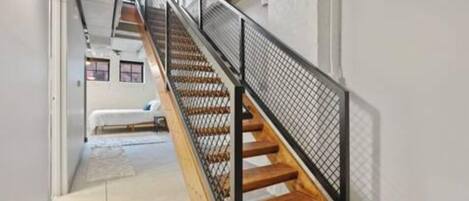 Una escalera de madera con barandillas de metal negro que sube a un piso superior.