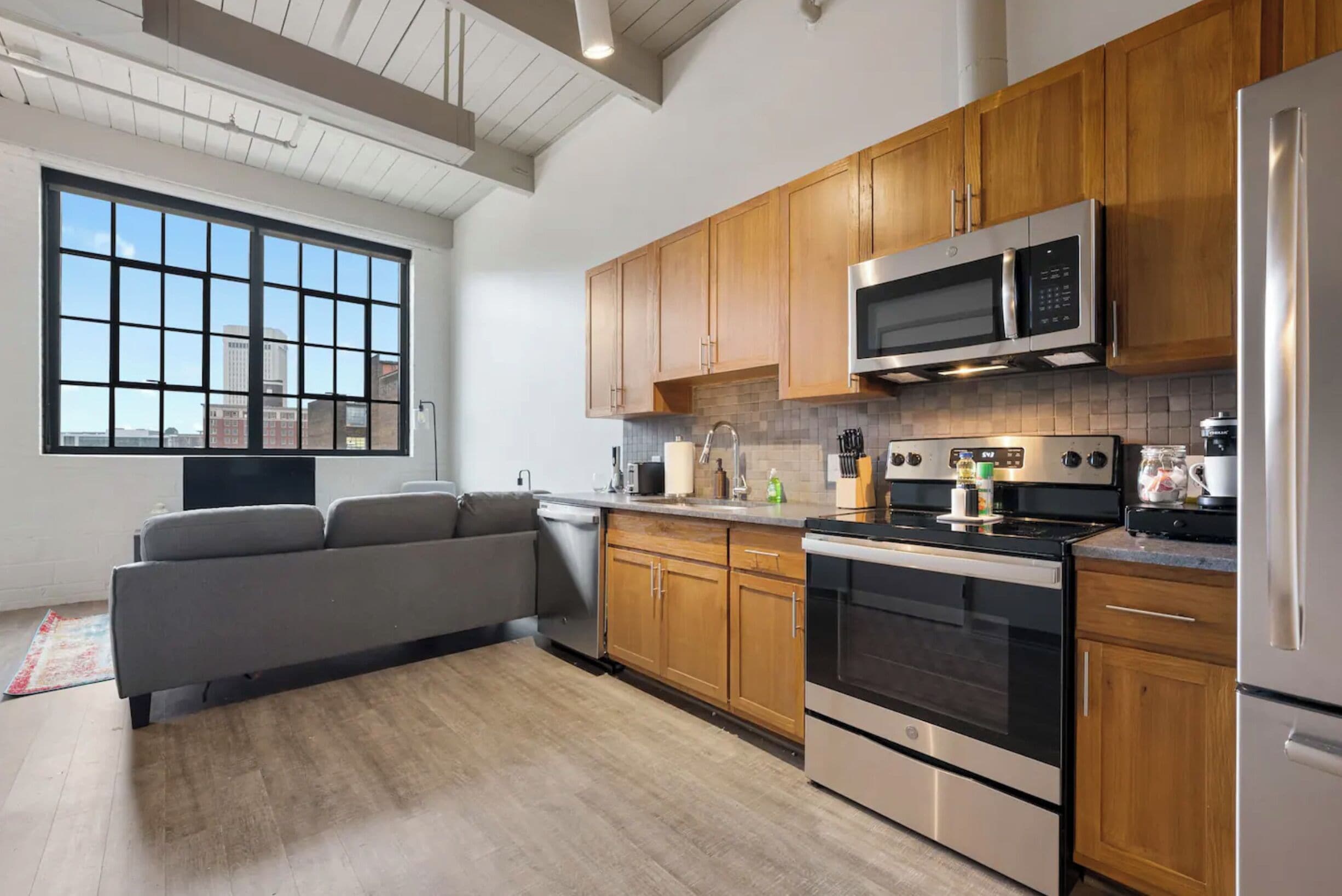 Una cocina moderna con armarios de madera, electrodomésticos de acero inoxidable y un amplio ventanal con vistas a la ciudad.