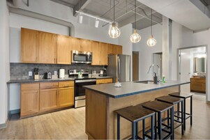 Una cocina moderna con armarios de madera, electrodomésticos de acero inoxidable y una isla central con taburetes.
