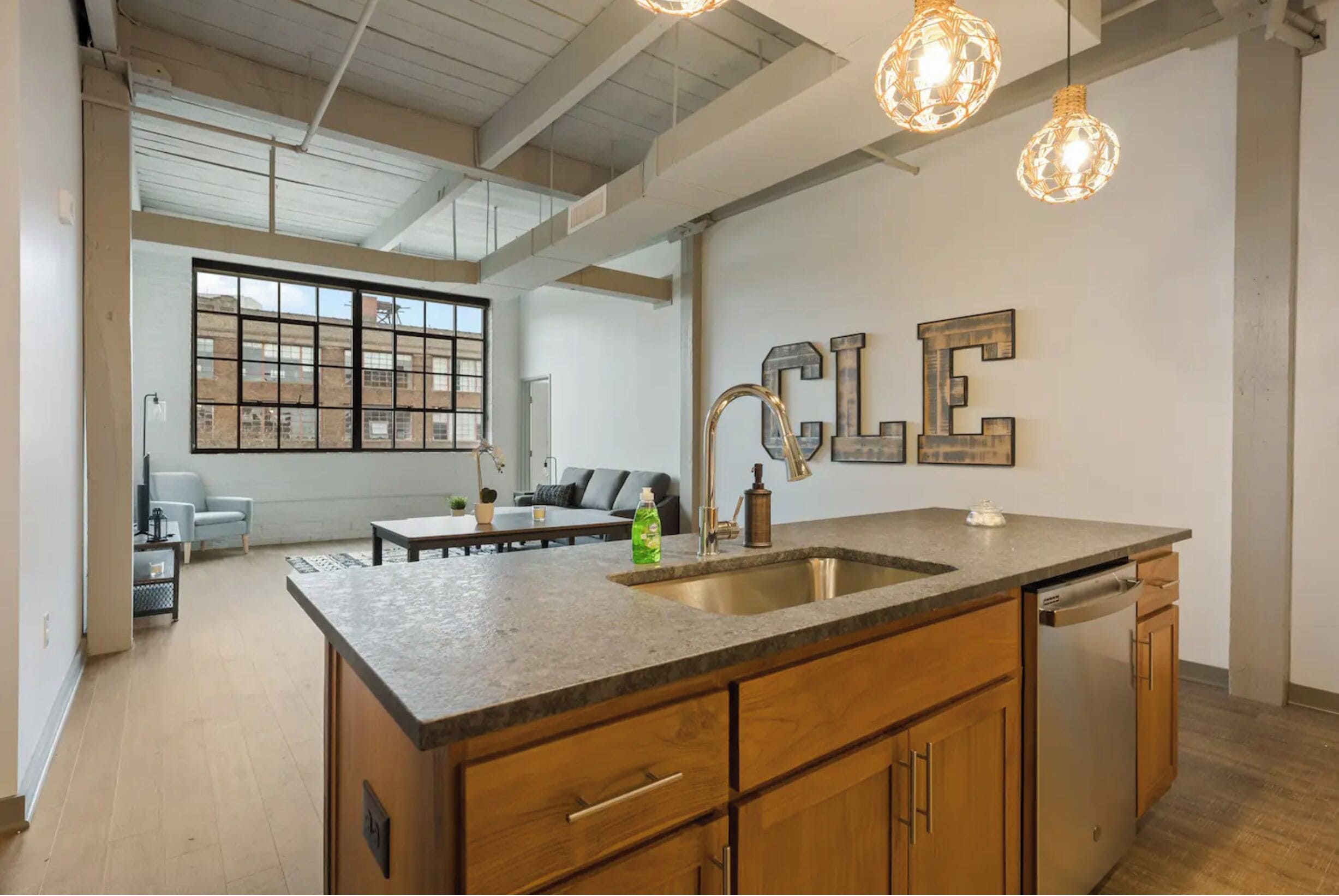 A modern kitchen with a large island, stainless steel appliances, and pendant lighting.
