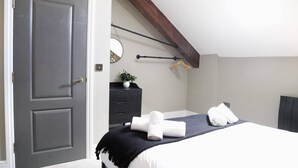 Un dormitorio con cama, cómoda, espejo y lámpara colgante.