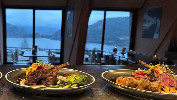 Tres platos de comida con vistas a un lago y montañas al fondo.